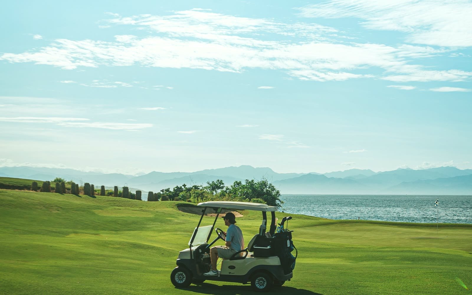 A lone golf cart out on a coastal course, far from the clubhouse